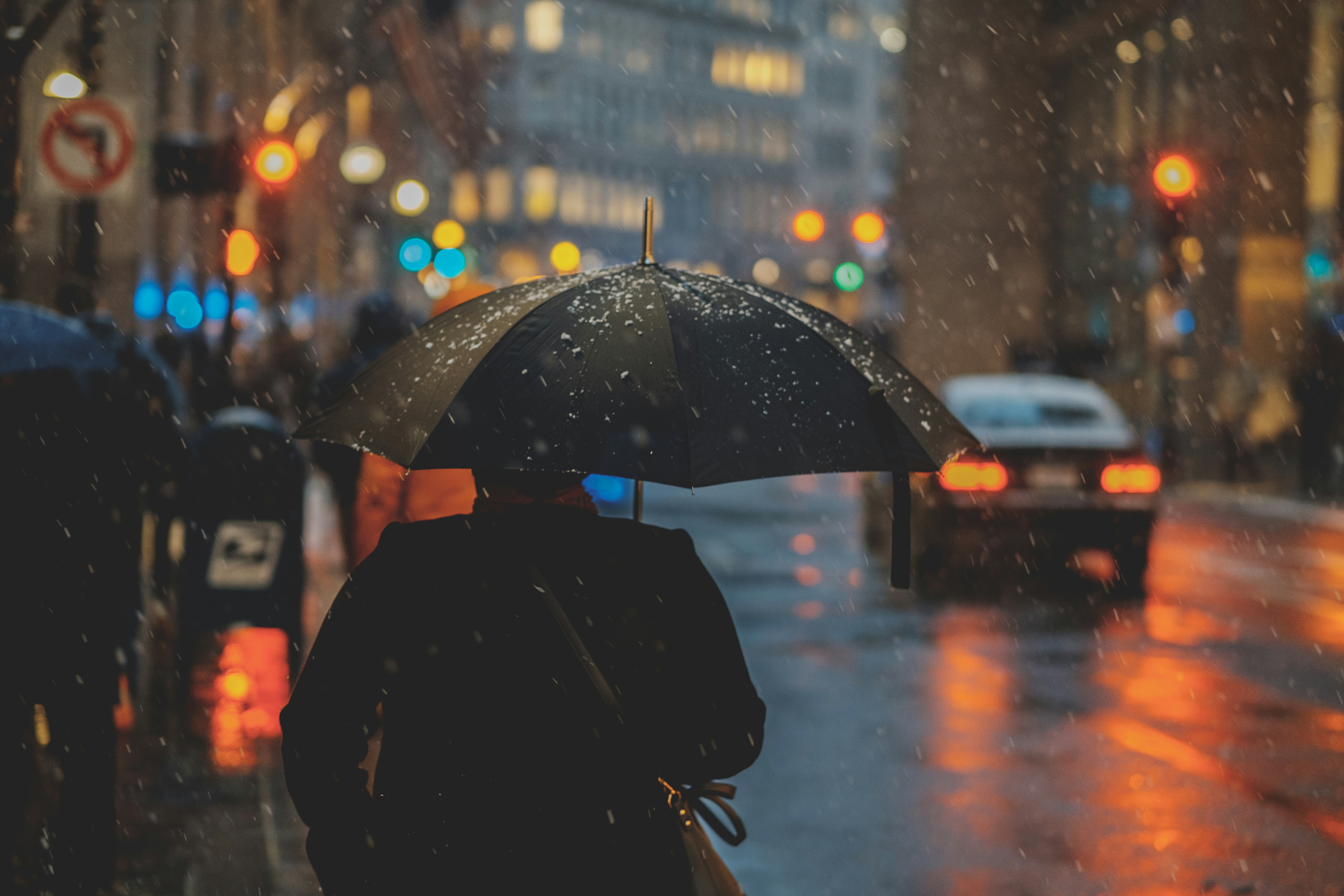 Un homme avec un parapluie ouvert au-dessus de la tête marche en ville sous la pluie
